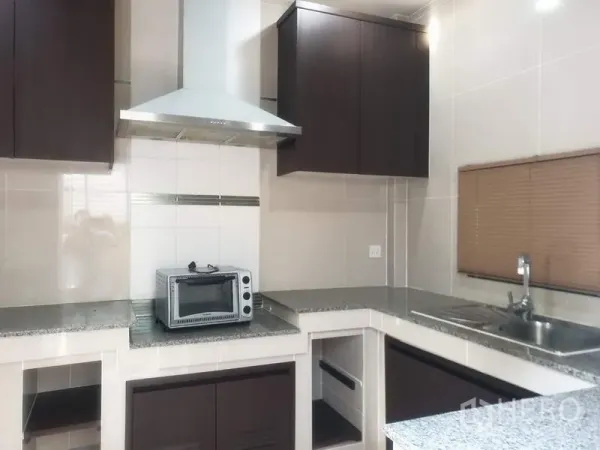 Detached House for sale in Bang Kapi, Bangkok - U-shaped kitchen with granite countertops, range hood and ample cabinetry.