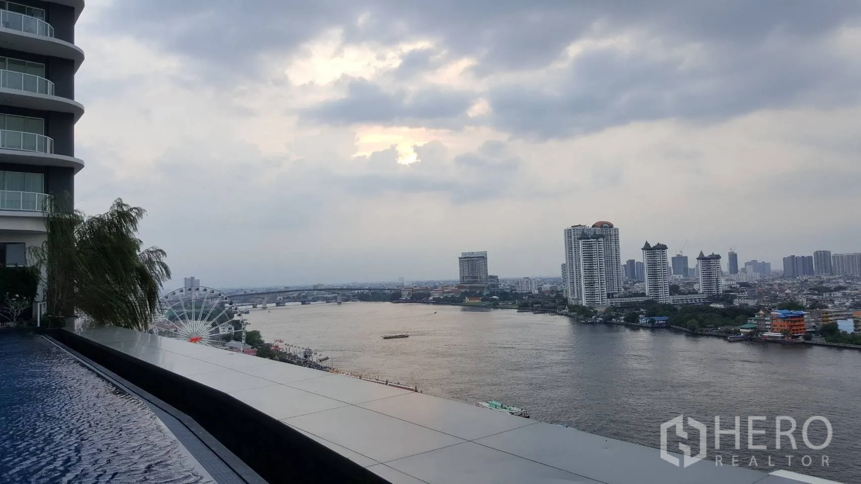Condominium for rent in Bang Kho Laem, Bangkok - Infinity-edge pool facing the Chao Phraya River with the Asiatique Ferris wheel and skyline in view.