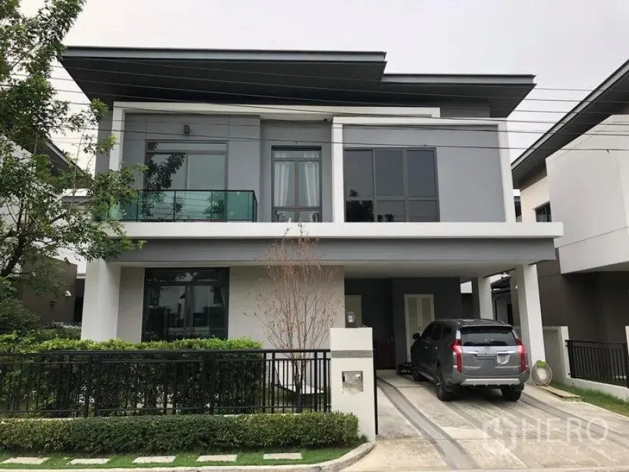 Detached House for rent in Saphan Sung, Bangkok - Modern two-storey detached house with carport, driveway and glass balcony behind a gated hedge.