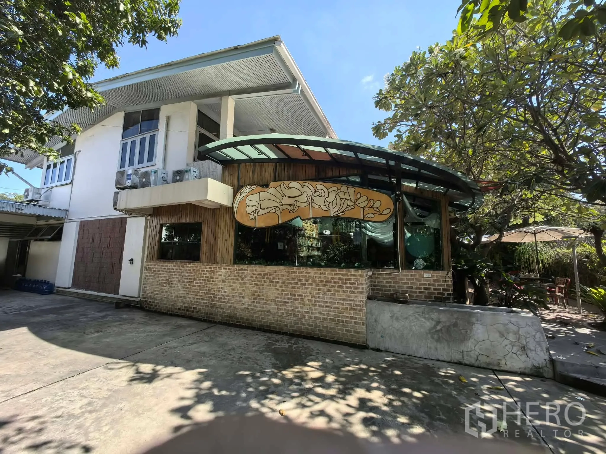 独栋房屋 for rent in Watthana, Bangkok - 正立面带弧形玻璃亭，与两层主体房屋相连。