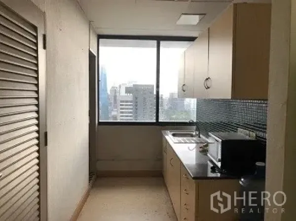 Office Space for rent or sale in Bang Rak, Bangkok - Compact office pantry with sink, cabinets, and city-facing window.