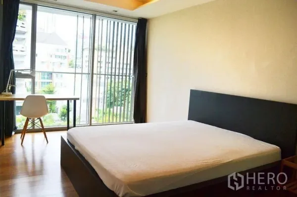 公寓 出租在Watthana, Bangkok - 主卧宽敞，设大窗、书桌，可见城市绿意景观。