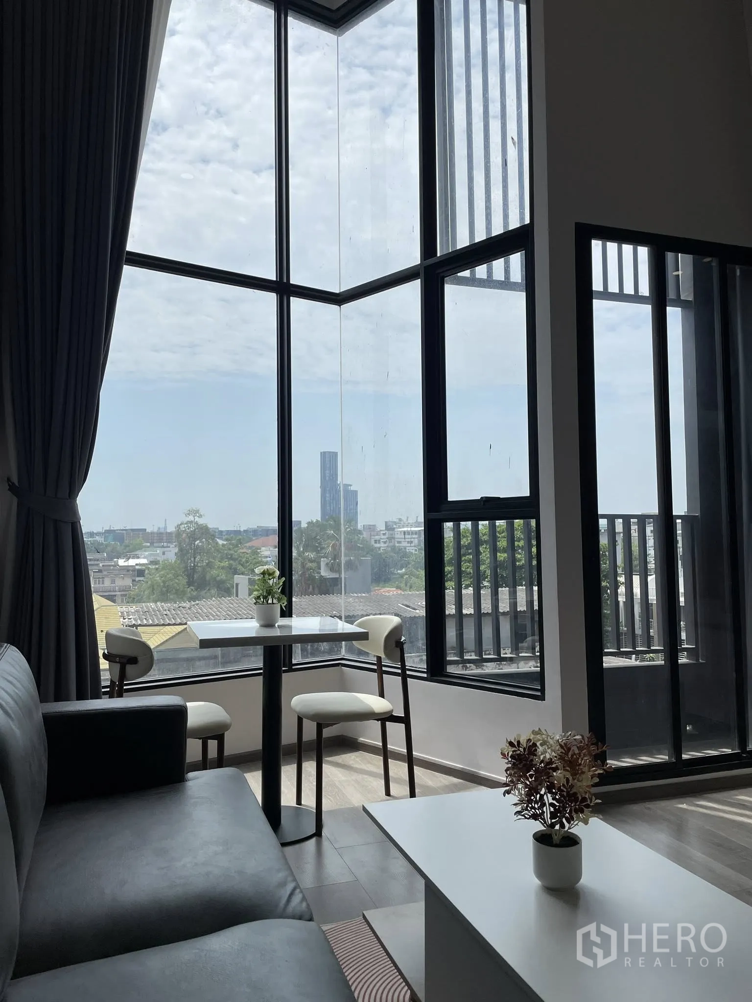 公寓 for rent in Khlong Toei, Bangkok - 转角落地窗的客厅，配小型餐桌椅与城市景观。