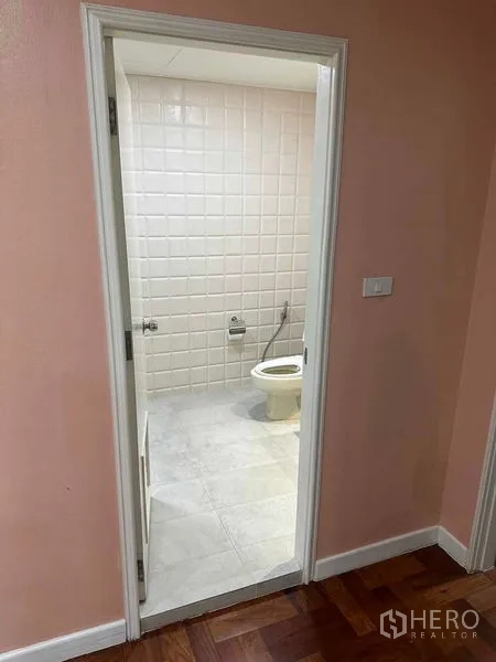 Condominium for sale in Bangkok - Doorway from bedroom to bathroom with light tile and sanitaryware visible.