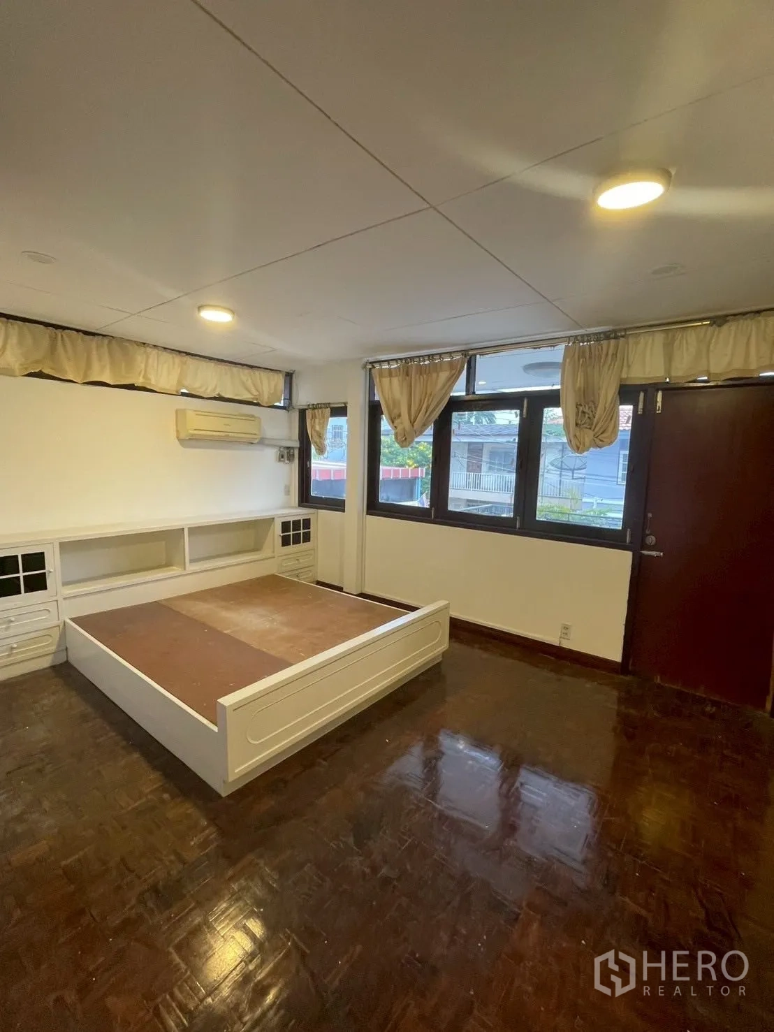 Detached House for rent in Watthana, Bangkok - Bedroom with large windows, built-in platform bed, air conditioner and wood floors.