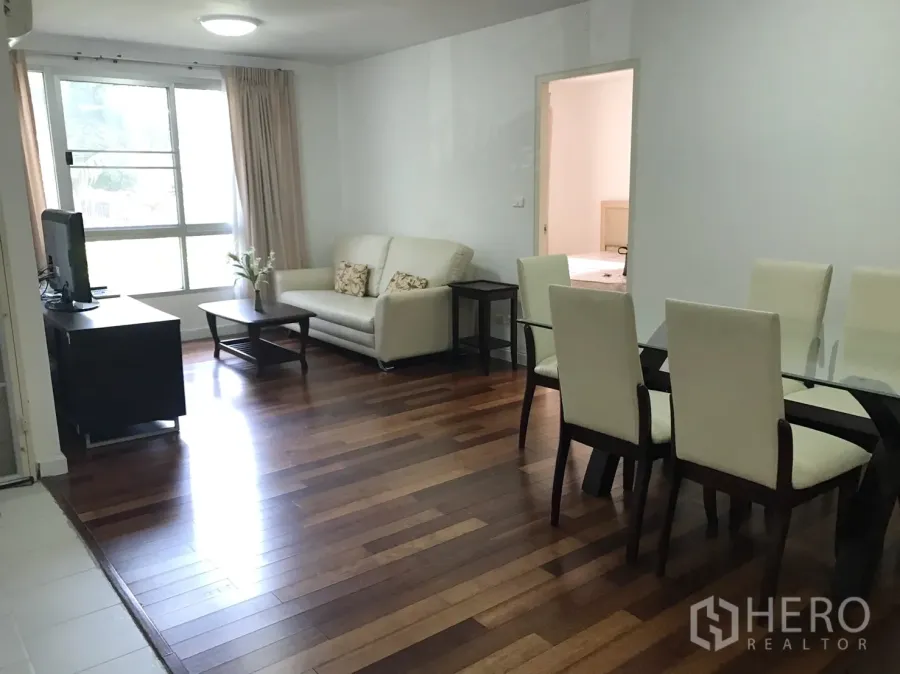 公寓 出租在Watthana, Bangkok - 采光良好的客餐厅，木地板、玻璃餐桌、电视柜与大窗。
