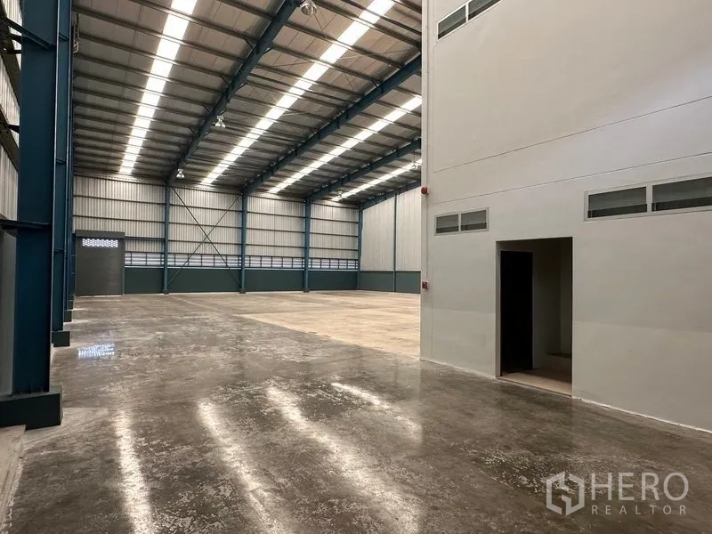 Factory for rent in Bang Phli, Samut Prakan - Warehouse aisle beside the office wall showing polished floor and an access door.