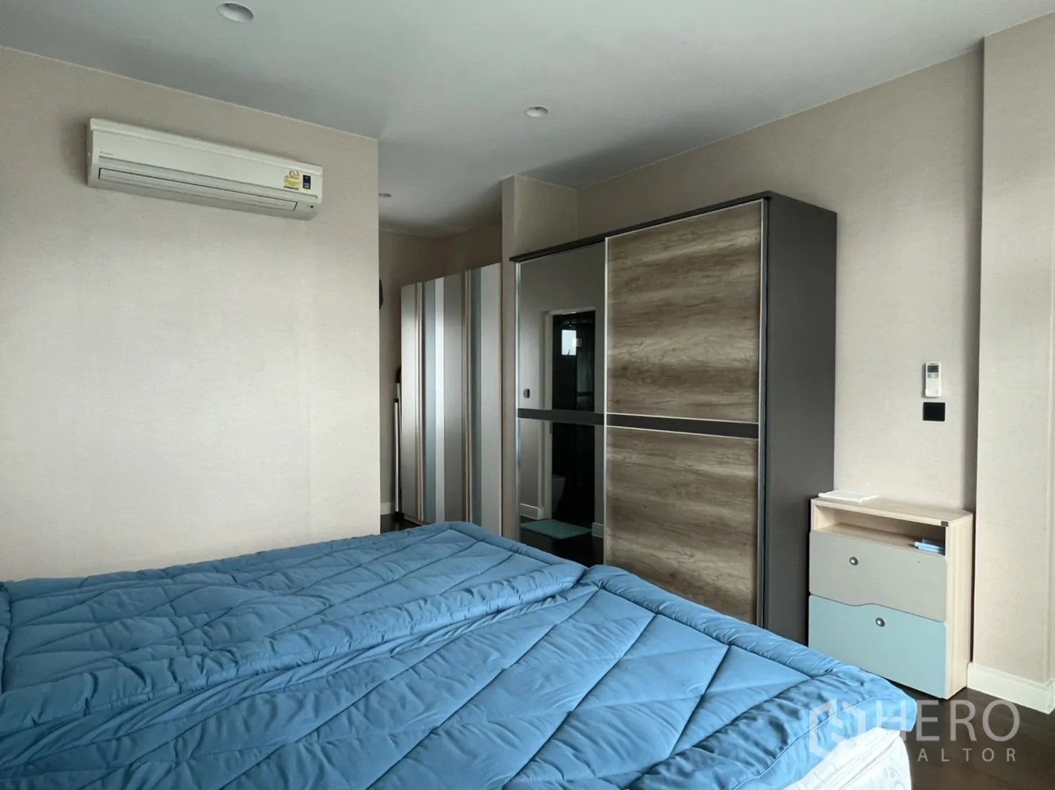 Detached House for rent or sale in Bang Kapi, Bangkok - Bedroom angle showing sliding-door wardrobe, bedside cabinet and doorway to ensuite.