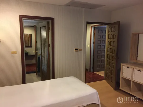 Condominium for rent in Pathum Wan, Bangkok - Second angle of the twin bedroom showing doors to the bathroom and a dresser with storage baskets.