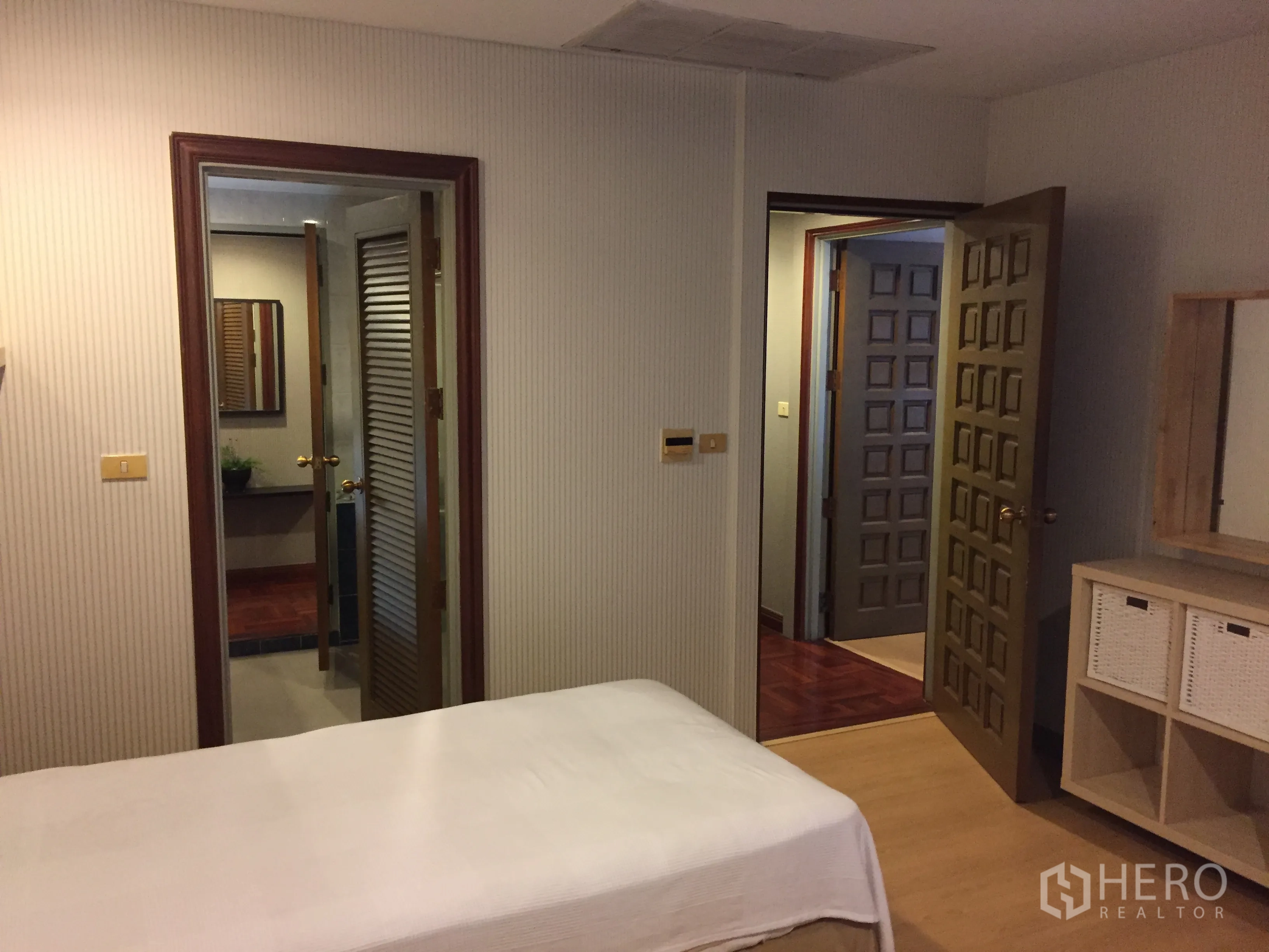 Condominium for rent in Pathum Wan, Bangkok - Second angle of the twin bedroom showing doors to the bathroom and a dresser with storage baskets.