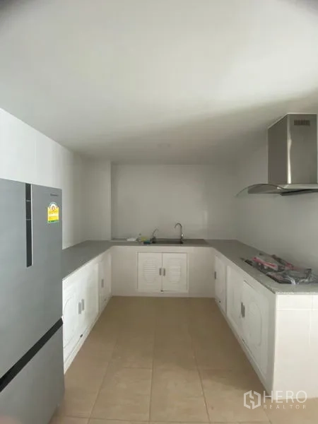 Condominium for rent in Sathon, Bangkok - Enclosed kitchen with L-shaped counters, stainless hood, double sink, and a refrigerator.