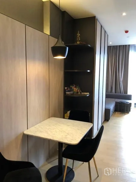 Condominium for rent in Din Daeng, Bangkok - Compact dining corner with marble-top table, pendant light, and built-in shelves beside wood paneling.