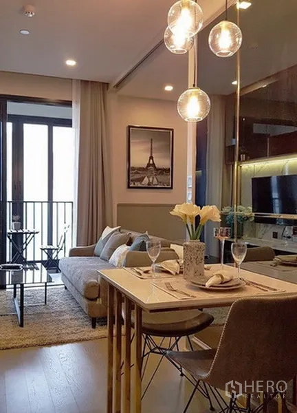Condominium for rent in Watthana, Bangkok - Dining corner with marble-top table and globe pendant lights opening to the living area and balcony.