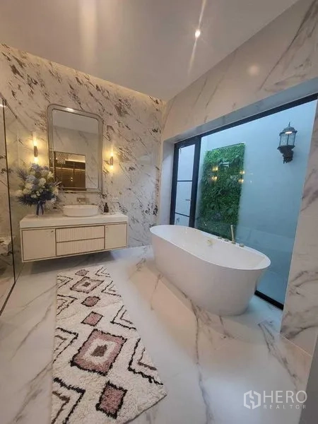 Detached House for rent in Saphan Sung, Bangkok - Luxury marble bathroom with freestanding tub beside a garden-view window.
