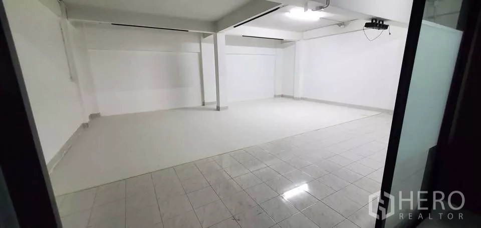 Office Space for rent in Suan Luang, Bangkok - Empty tiled room viewed from doorway with white walls and ceiling lights.