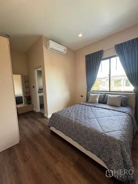 Detached House for rent or sale in Bang Phli, Samut Prakan - Cozy bedroom with double bed, wood flooring, window drapes and en-suite access.