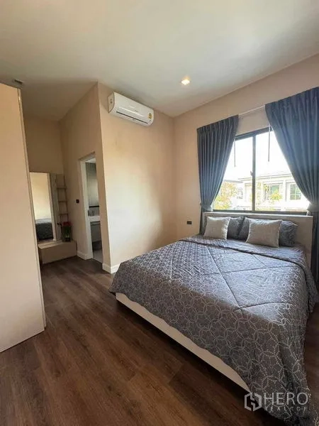 Detached House for rent or sale in Bang Phli, Samut Prakan - Cozy bedroom with double bed, wood flooring, window drapes and en-suite access.