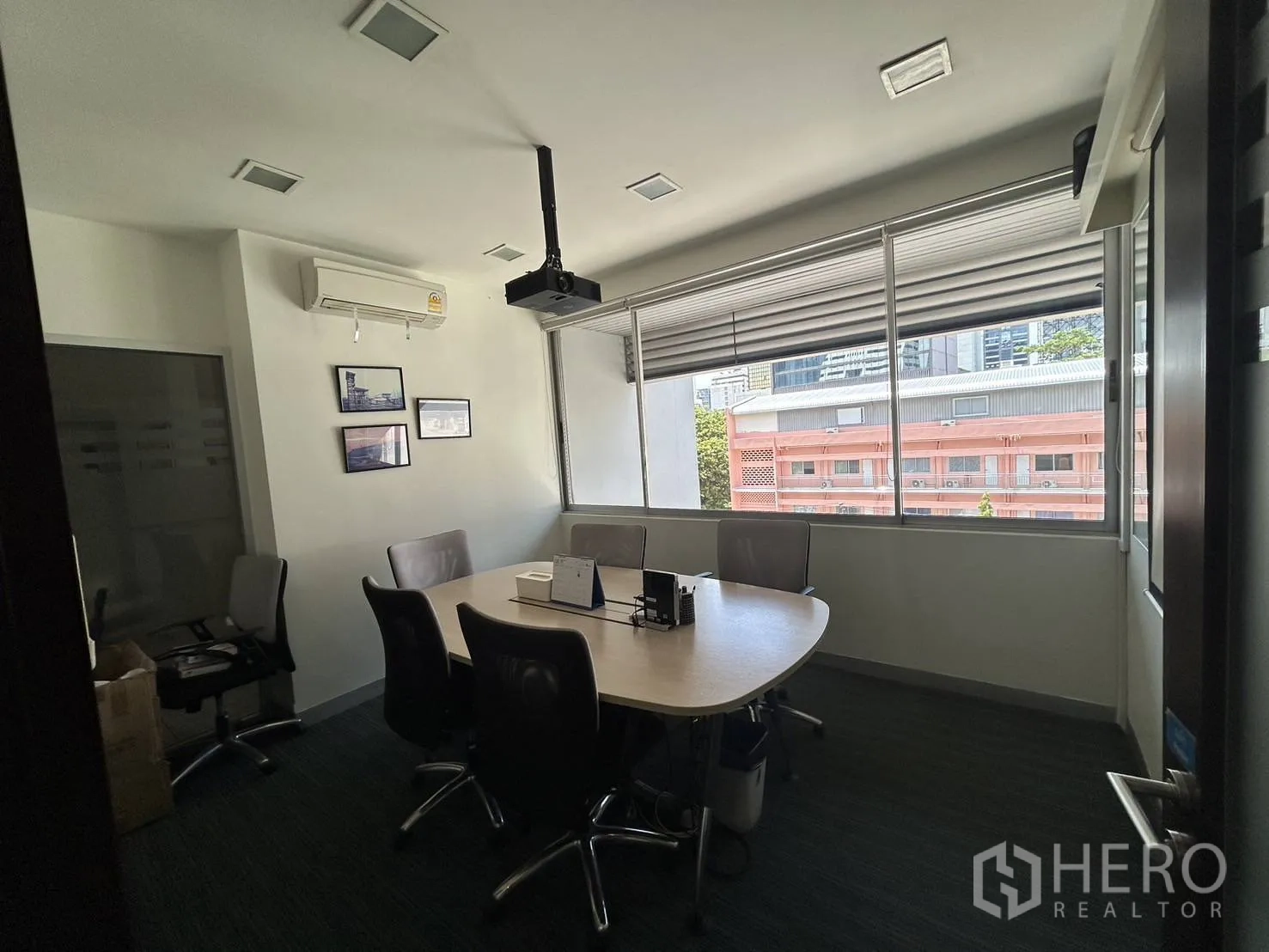 Office Space for rent - Small meeting room with round table, ceiling-mounted projector and wide windows.