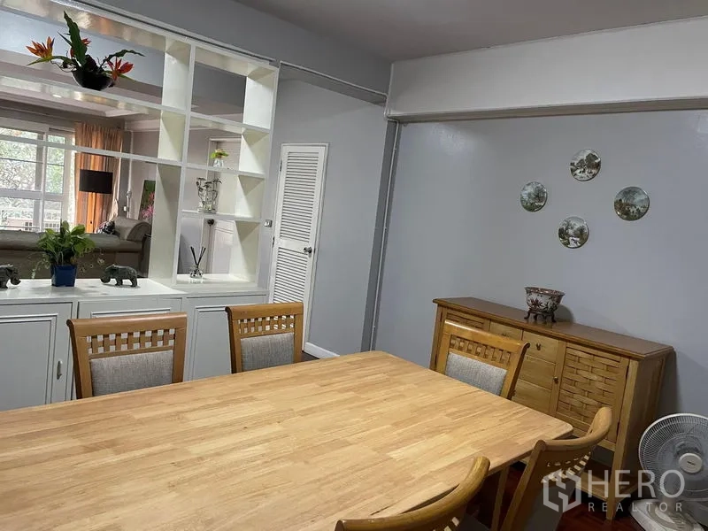 Condominium for rent in Watthana, Bangkok - Dining room with partition shelving and sideboard overlooking the living area.
