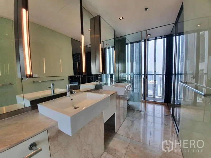 Condominium for rent in Sathon, Bangkok - Luxury bathroom with double vanity, full-height mirrors and glass partitions near balcony.