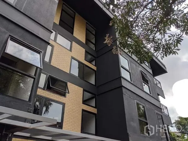 办公空间 出租 - 低层当代建筑外立面，黑色与砖墙搭配，多扇可开启窗与阳台。