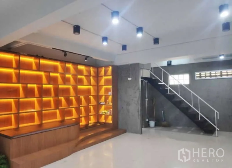 Home Office for rent in Khlong Toei, Bangkok - Showroom-style space featuring illuminated wooden shelving, concrete walls, and a staircase.