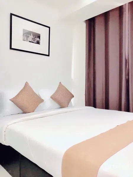 Condominium for rent or sale in Khlong Toei, Bangkok - Cozy bedroom with white bedding, tan runner, and dark blackout curtains.