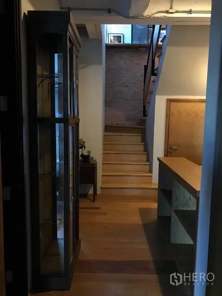 联排别墅 出售在Wang Thonglang, Bangkok - 楼梯与过道，外露天花管线、木楼梯及展示柜。