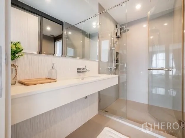 Condominium for sale in Khlong Toei, Bangkok - Contemporary bathroom with wide vanity, mirrors, and glass-enclosed shower.