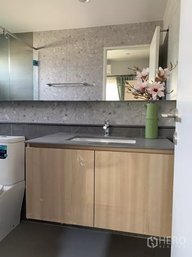 Detached House for rent in Bang Kapi, Bangkok - Modern bathroom with stone vanity, large mirror and glass shower enclosure.
