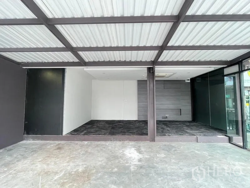 Office Space for rent in Bang Na, Bangkok - Raised carpeted workspace with ceiling cassette air-conditioner and grey feature wall behind glass.