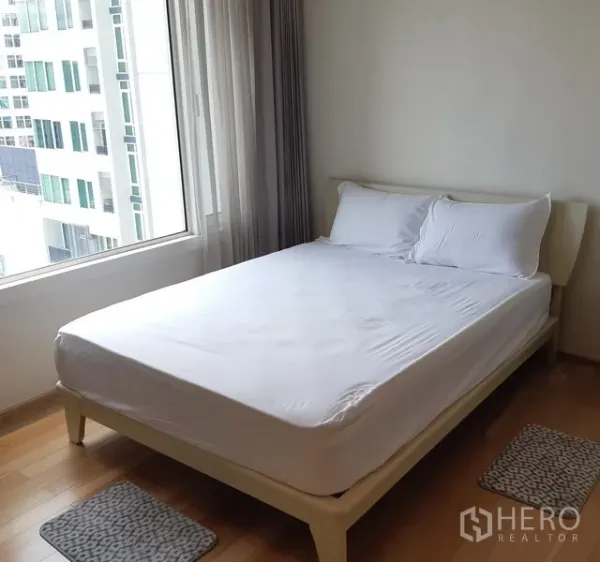 Condominium for rent in Khlong Toei, Bangkok - Cozy bedroom with double bed, large window and city view in a 1-bedroom condo.