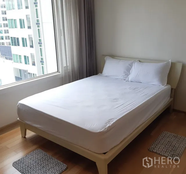 Condominium for rent in Khlong Toei, Bangkok - Cozy bedroom with double bed, large window and city view in a 1-bedroom condo.