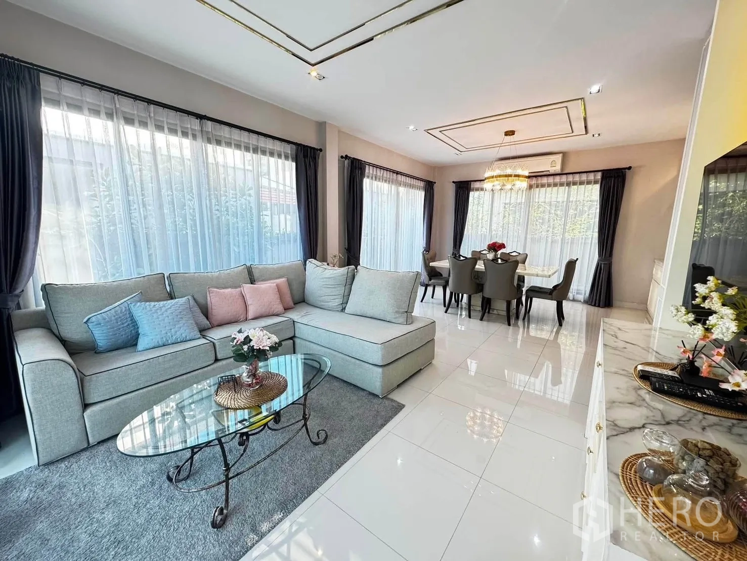 Detached House for rent in Saphan Sung, Bangkok - Open-plan living room with L-shaped sofa, glass coffee table, and large windows.