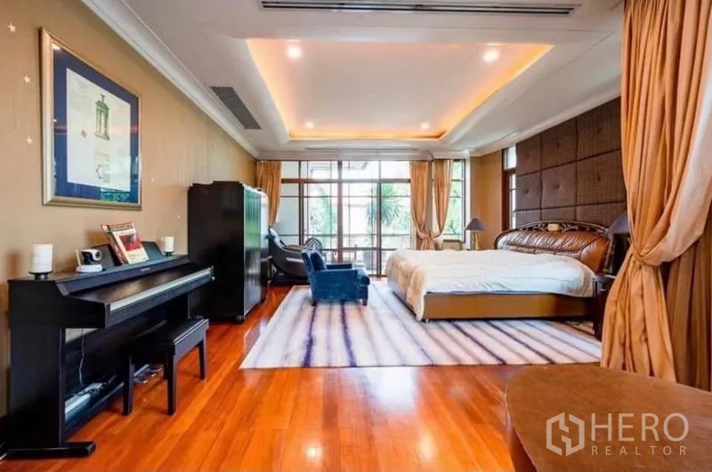 独立式住宅 出租在Khlong Toei, Bangkok - 主卧宽敞，木地板、吊顶、大面积窗户，并设钢琴与休息区。
