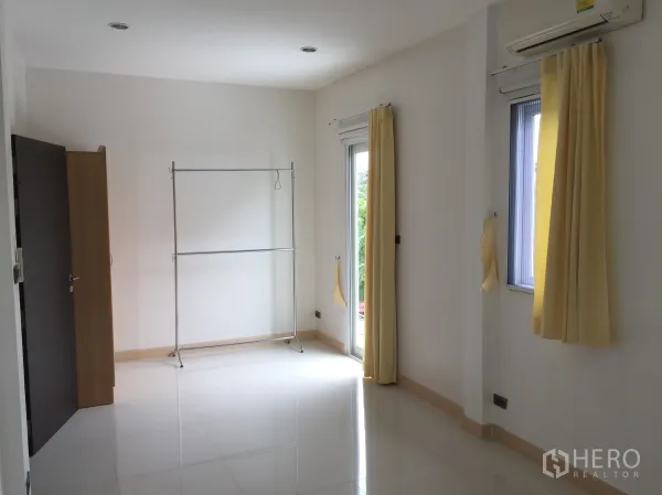 联排别墅 出租在Din Daeng, Bangkok - 宽敞白色房间，黄色窗帘、分体空调与阳台门。