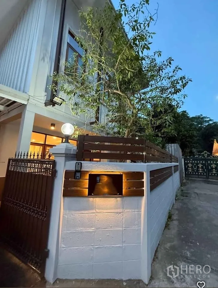 独立式住宅 出租在Khlong Toei, Bangkok - 夜景外观，转角围墙、铁门与壁灯照明。