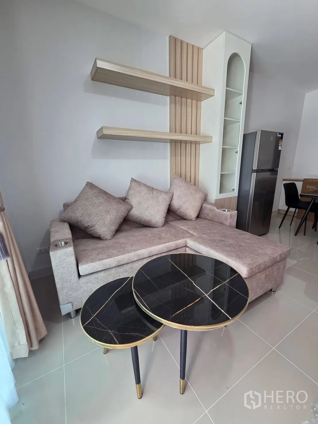 Townhouse for rent in Bang Phli, Samut Prakan - Bright living area with L-shaped sofa, nested black marble-top coffee tables, and floating shelves.