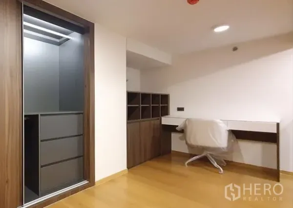 Condominium for sale in Watthana, Bangkok - Mezzanine study area with built-in desk, shelving, and closet on wood flooring.