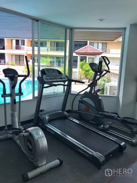 Condominium for rent in Khlong Toei, Bangkok - Fitness room with treadmill, exercise bike and cross trainer overlooking the pool.