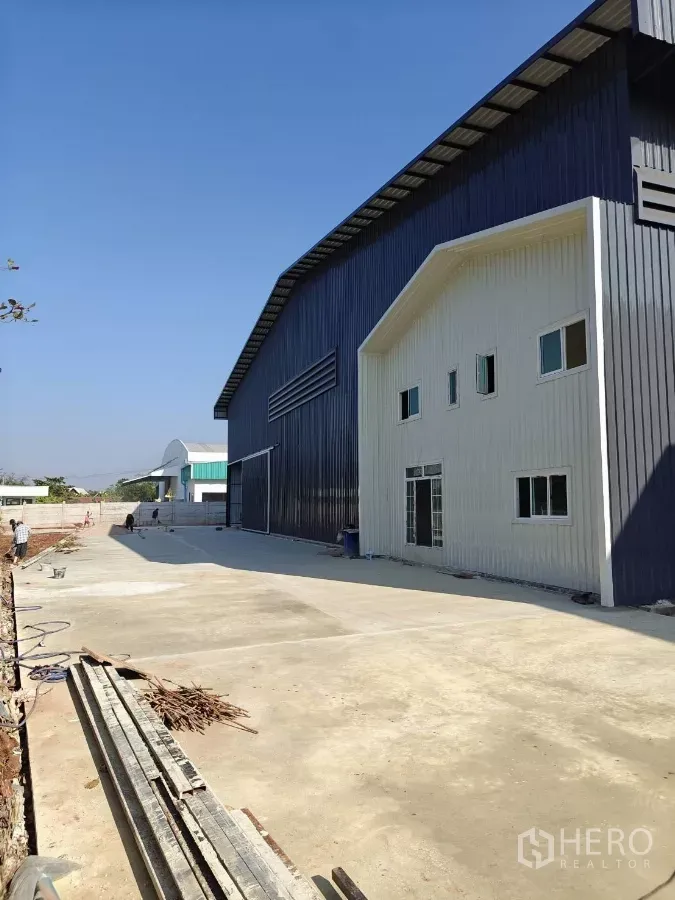 Factory for rent in Mueang Samut Sakhon, Samut Sakhon - Steel-clad factory exterior with attached two-storey office and wide concrete yard in Mueang Samut Sakhon.