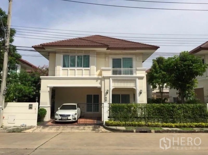 Detached House for rent or sale in Khlong Toei, Bangkok - Two-storey detached house exterior with tiled roof, gated carport and manicured hedge.