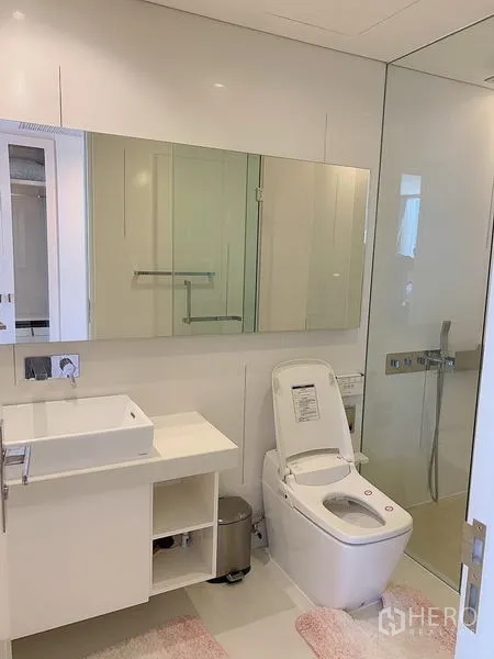 Condominium for sale - Bright bathroom with floating vanity, large mirror, smart toilet, and glass shower.