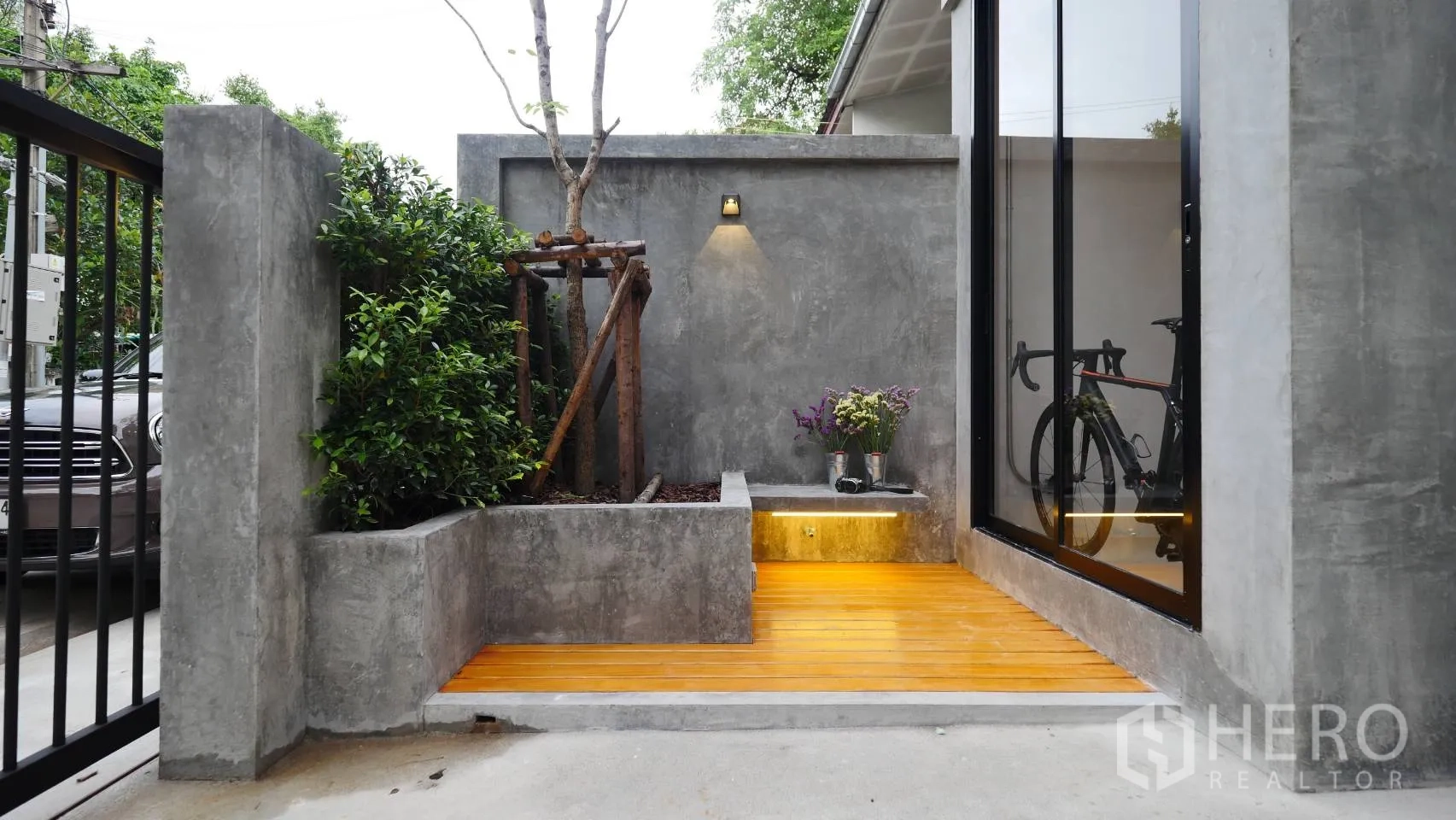 Townhouse for rent in Huai Khwang, Bangkok - Front patio with concrete planters, wood deck, wall light and sliding glass door.