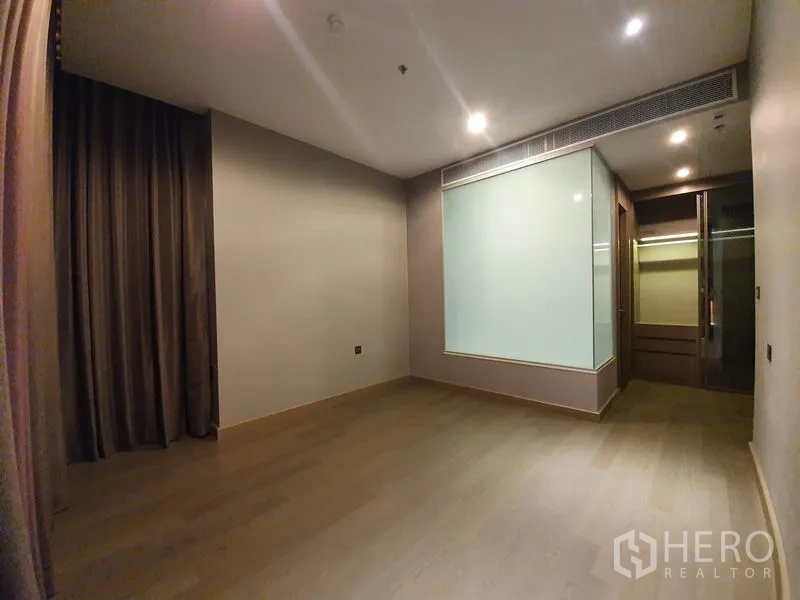 คอนโด ให้เช่าในHuai Khwang, Bangkok - ห้องนอนหลักพื้นไม้ ผนังกระจกฝ้า ไฟดาวน์ไลท์ พร้อมทางเข้าตู้เสื้อผ้า