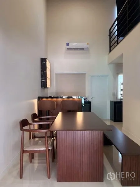 Townhouse for rent - Dining zone with long wooden table and bench under a high ceiling.