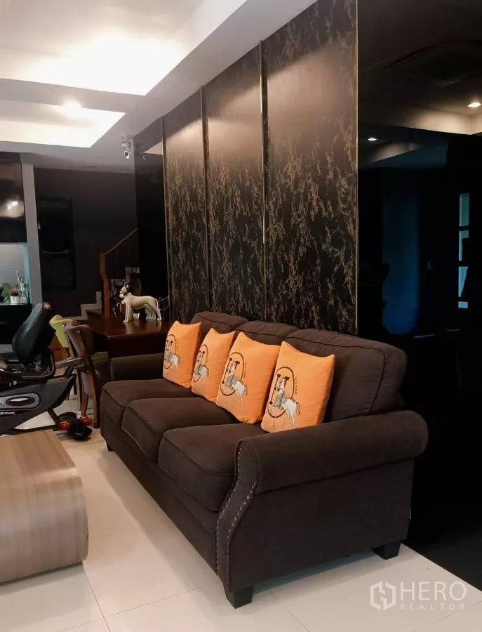 Detached House for rent or sale in Khan Na Yao, Bangkok - Living room with dark feature wall, soft sofa and dining space beyond.