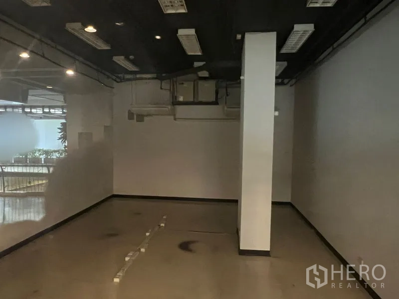 Retail Space for rent - Interior view with central column, dark exposed ceiling and air-conditioning ducts.