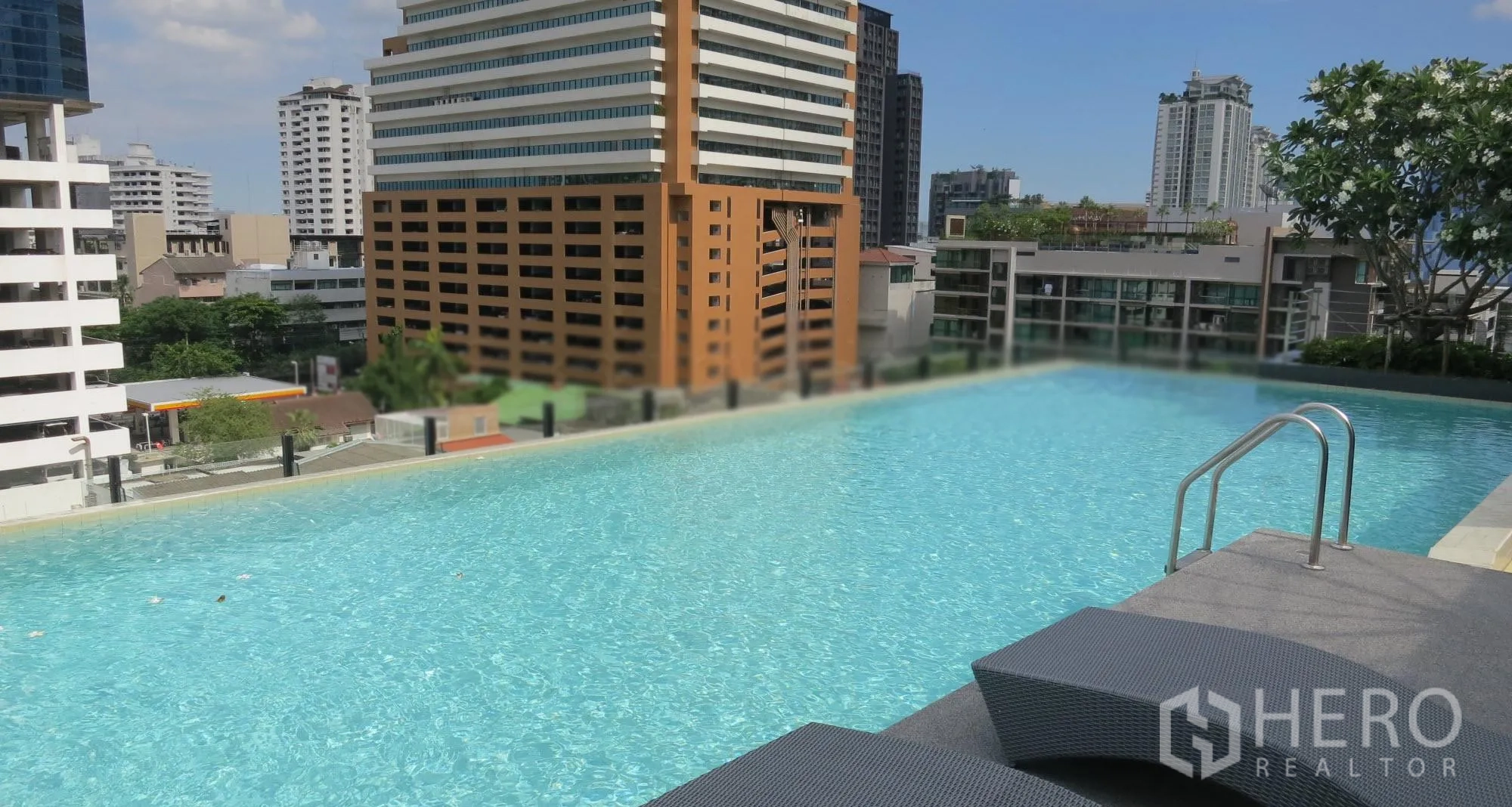 Condominium for rent or sale in Watthana, Bangkok - Rooftop infinity swimming pool with city skyline views and sun loungers near BTS Ekkamai.