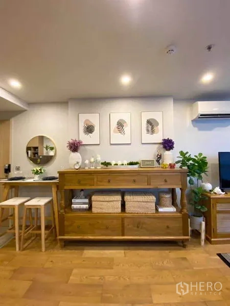 公寓 出售在Ratchathewi, Bangkok - 客厅墙面配木质收纳柜、装饰画与筒灯，带空调。